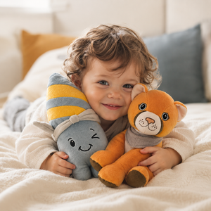 Fröhliches Kleinkind kuschelt auf dem Bett mit den Lenabies Nalu das Surfbrett und Tali die Puma Dame von Lenabo. Die weichen interaktiven Kuschelfiguren fördern Fantasie, emotionale Entwicklung und schaffen liebevolle Wohlfühlmomente im Kinderzimmer.
