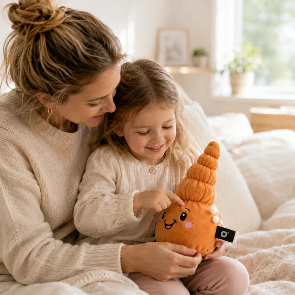 Mutter und Kind sitzen gemeinsam auf dem Sofa und entdecken das Lenabie Mia die Muschel, ein interaktives Audio-Kuscheltier für Kinder. Mia die Muschel begleitet die gemeinsame Hörspiel- und Vorlesezeit mit Kindergeschichten, Musik und altersgerechten Audioinhalten für das Kinderzimmer.